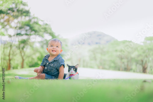 Cute boy with a kitten lying in the grass,portrait of baby with with his cat,pet