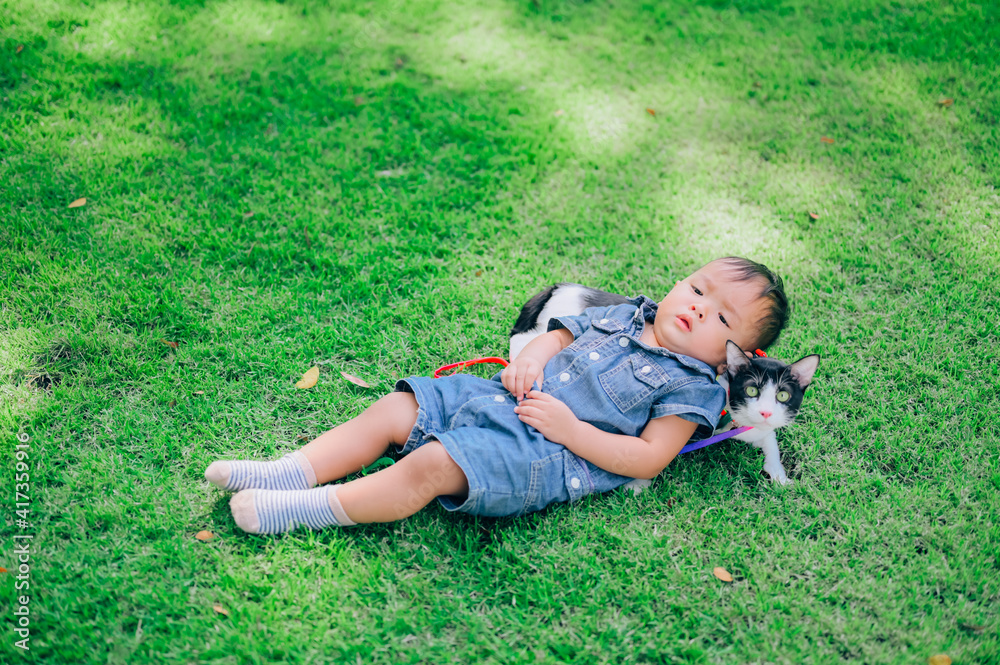 Cute boy with a kitten lying in the grass,portrait of baby with with his cat,pet Cute boy with a kitten lying in the grass,portrait of baby with with his cat,pet