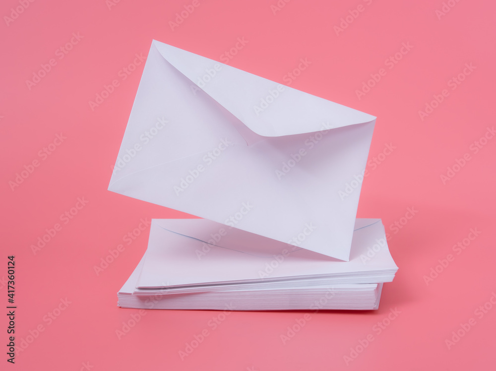 Blank white paper envelope falling on pink background with copy space Blank white paper envelope falling on pink background with copy space