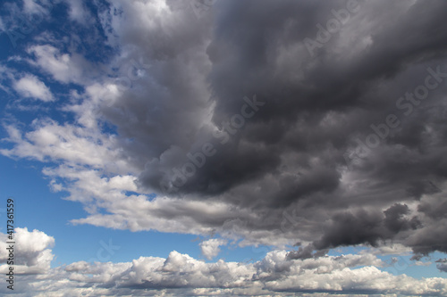 Storm sky. Dark grey and white big cumulus clouds against blue sky background, cloud texture, thunderstorm