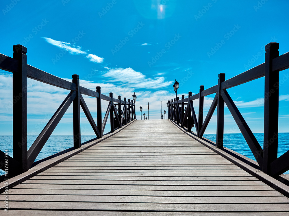 Fototapeta premium Sandy beach and wooden pier on the Costa del Sol in Marbella, Spain