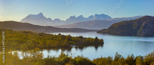 Panoramic view of a landscape with mountains and lake in late afternoon light