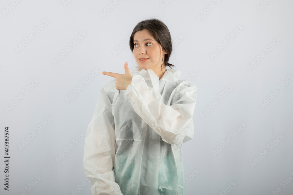Portrait of young female doctor scientist in defensive lab coat pointing away Portrait of young female doctor scientist in defensive lab coat pointing away