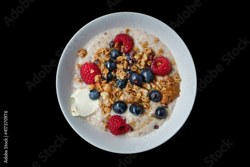 Top view of healthy cereal and oatmeal breakfast with berries and nuts in a white bowl. Ideal for those suffering from Irritable bowel syndrome or Small intestinal bacterial overgrowth. Isolated.
