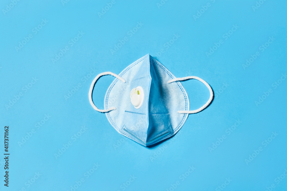 The safest N95 face mask on blue background. Close-up view of medical protective respirator mask from above The safest N95 face mask on blue background. Close-up view of medical protective respirator mask from above