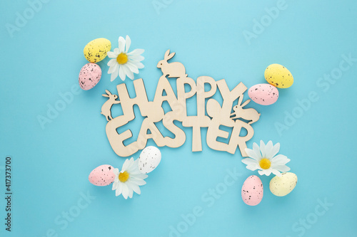 Happy Easter sign with eggs and daisies on a blue background © Daniel