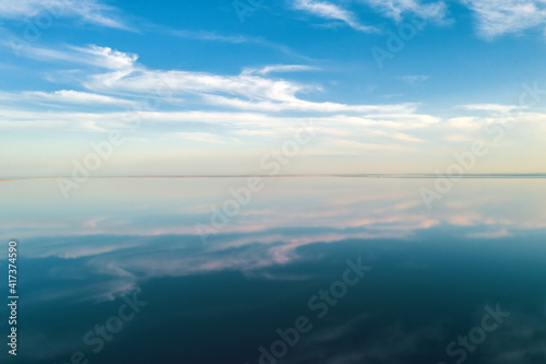 Salt lake water under blue sky with fluffy clouds in summer day. Creative color concept