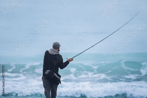 Back shot of an angler about to cast the line. Selective focus.