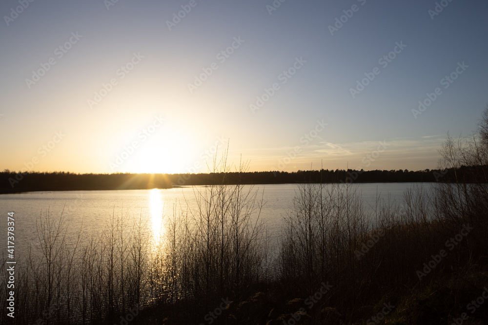 Dramatic and colorful sunset over a forest lake reflected in the water. Blakheide, Beerse, Belgium. High quality photo