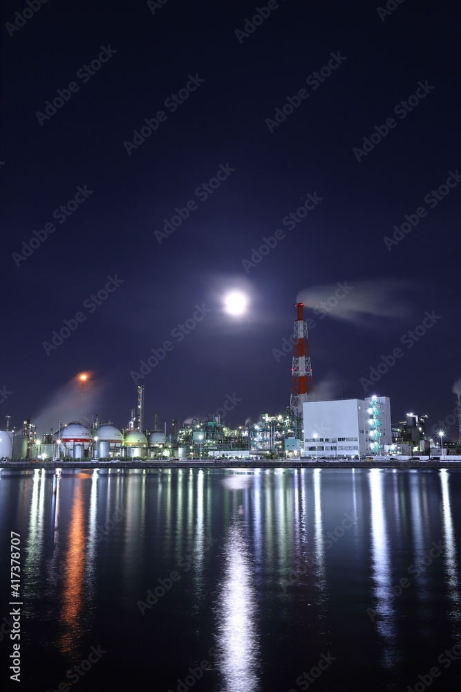 明るい月と水辺にある工場
