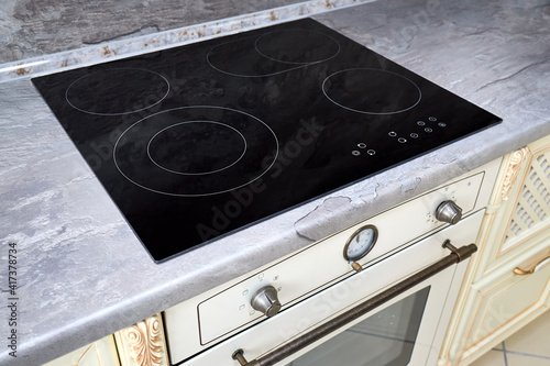 Obraz na plátně Modern kitchen luxurious interior with black induction or electric hob stove cooker with ceramic top surface with marble countertop and wall decorated with stone