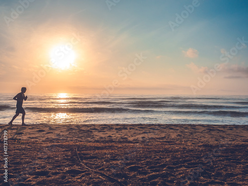 silhouette of jogging man on beach in the morning at sunrise.