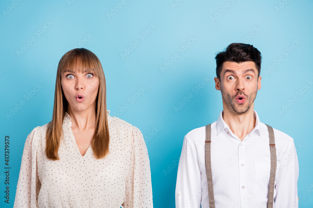 Photo of funny impressed young couple wear white outfit big eyes isolated blue color background Photo of funny impressed young couple wear white outfit big eyes isolated blue color background