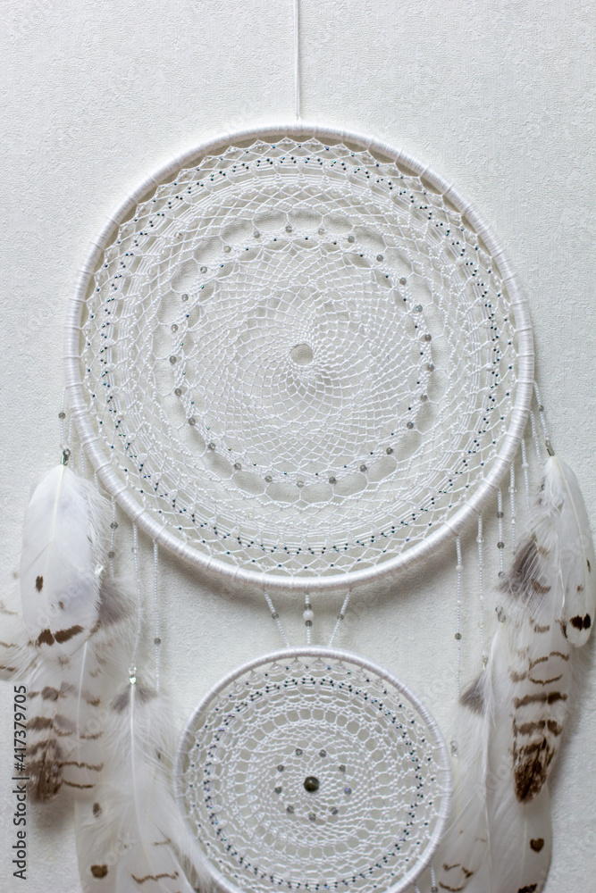 Handmade dream catcher with feathers threads and beads rope hanging on white background Handmade dream catcher with feathers threads and beads rope hanging on white background