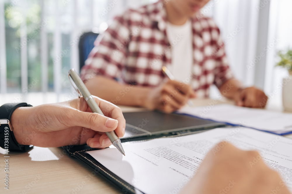 Close-up image of business people reading and discussing terms of contract at meeting Close-up image of business people reading and discussing terms of contract at meeting