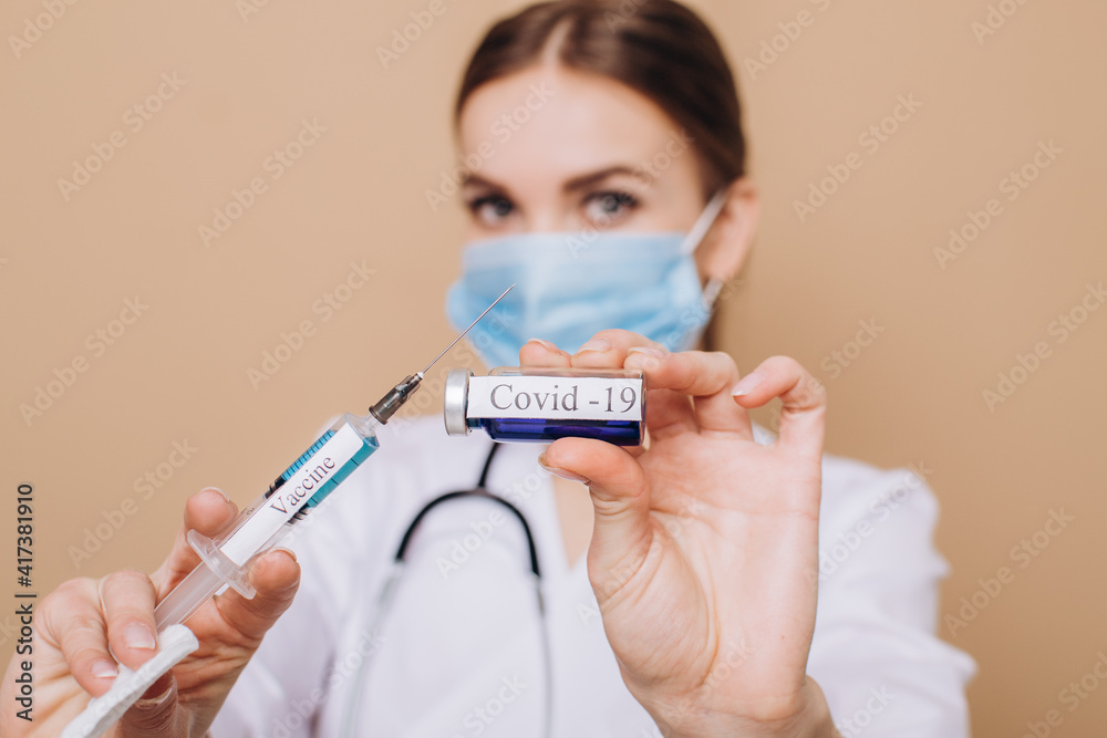 female doctor in a white coat holding a syringe with covid-19 vaccine close-up. Vaccination concept.