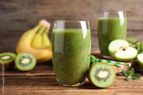 Delicious kiwi smoothie and fresh fruits on wooden table