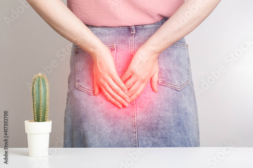 A cactus on the background of a woman in a denim skirt is holding her anus with her hands. Bowel problems, constipation and diarrhea concept. Obstructed bowel syndrome photo