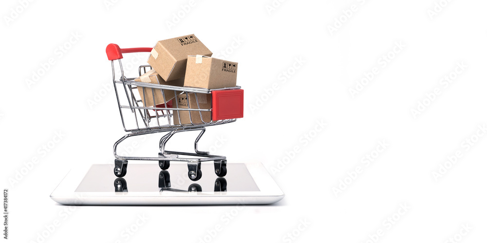 Isolated of Shipping paper boxes inside Red shopping cart trolley on tablet with white background and copy space , Online shopping and e-commerce concept.