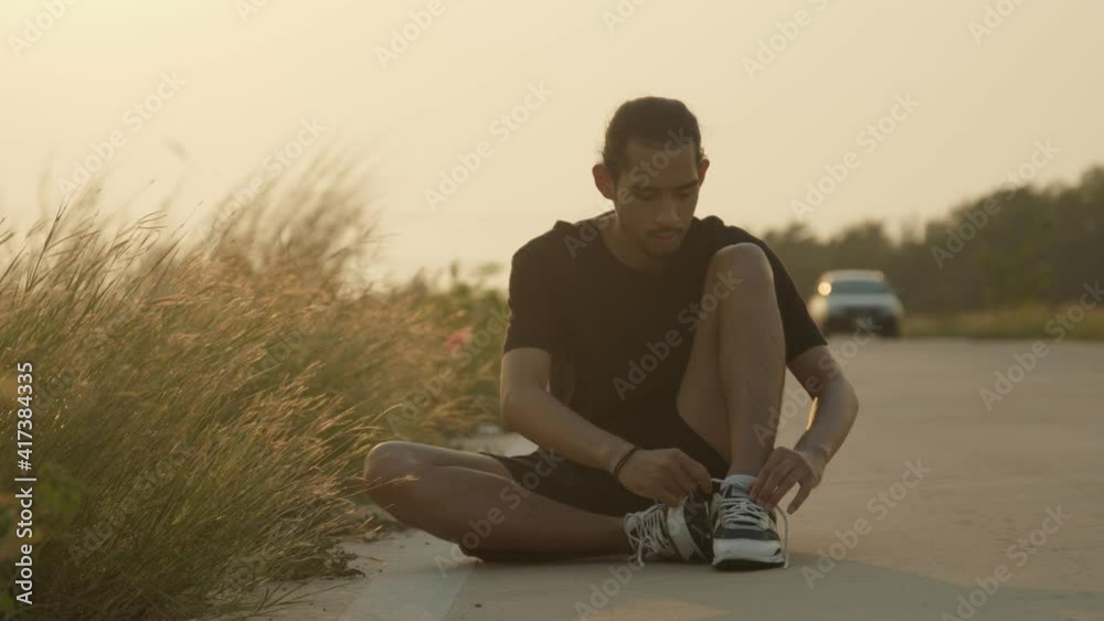 Asian sport man tie shoelaces on street in countryside with fresh and clear air, runner preparing to run and workout for good healthy, healthy care concept Asian sport man tie shoelaces on street in countryside with fresh and clear air, runner preparing to run and workout for good healthy, healthy care concept