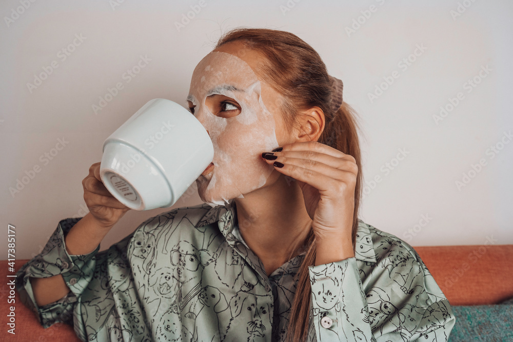 Girl applies cream to face and drinking coffee at home. Girl applies cream to face and drinking coffee at home.