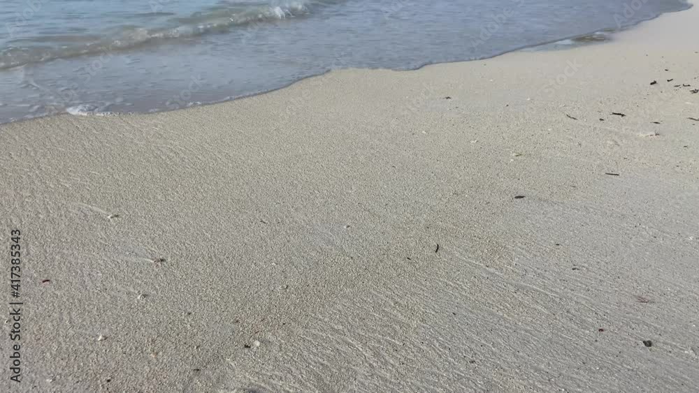 Close up of Caribbean Sea weaves splashing on the white sand of a beach during clear, sunny day Close up of Caribbean Sea weaves splashing on the white sand of a beach during clear, sunny day