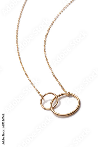 Cropped close-up of elegant golden necklace with two silver interlocked rings. The stylish jewelry is isolated on the white background. 