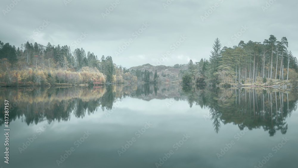 Reflection of trees in the water.Tarn Hows, Lake District, Cumbria, UK.Painterly and dreamlike landscape scenery.Nature background. Reflection of trees in the water.Tarn Hows, Lake District, Cumbria, UK.Painterly and dreamlike landscape scenery.Nature background.