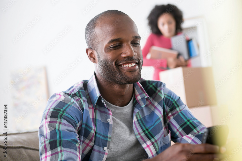 Mid adult man using cell phone, woman in background Mid adult man using cell phone, woman in background