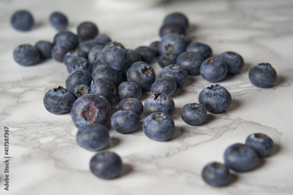 A group of fresh blueberries on a white and black marble table. A group of fresh blueberries on a white and black marble table.
