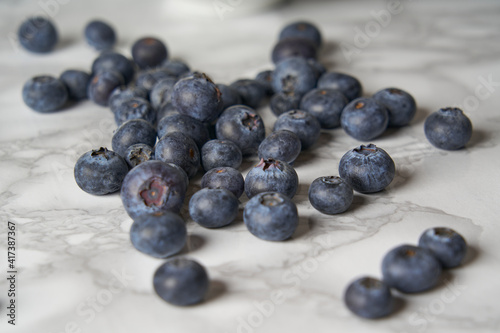 A group of fresh blueberries on a white and black marble table. 