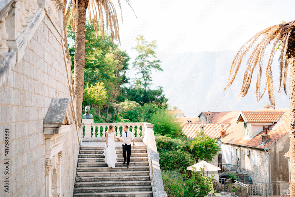 The bride and groom going down the ancient stairs of the Nativity of the Blessed Virgin Mary church in Prcanj