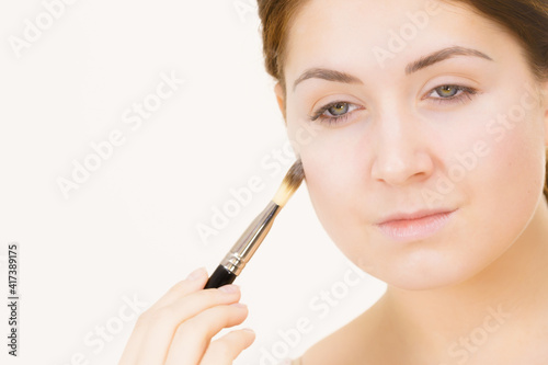 Girl with no makeup holds make up brush