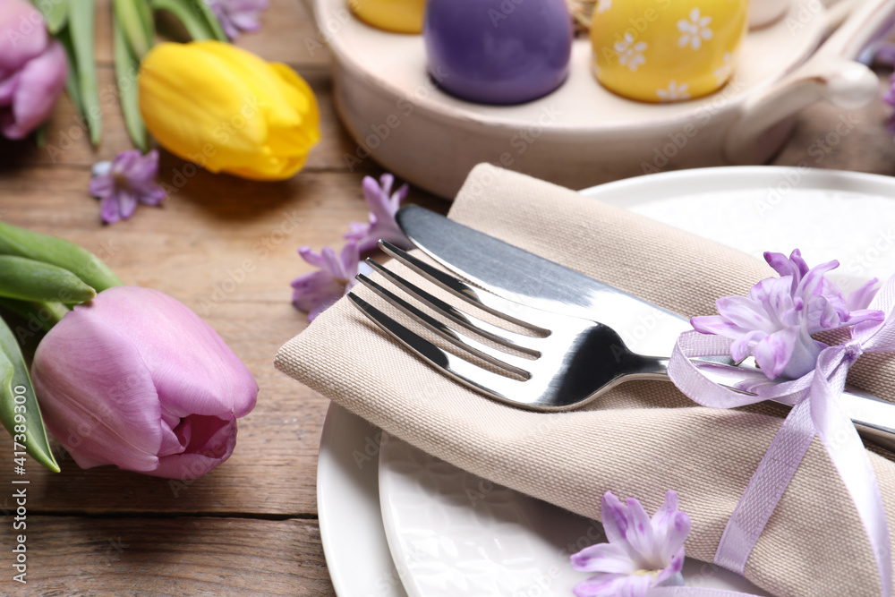 Festive Easter table setting with floral decor on wooden background, closeup Festive Easter table setting with floral decor on wooden background, closeup