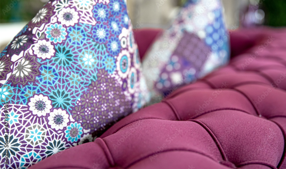 Purple velvet fabric modern sofa with sunken buttons and colorful decorative pillows.