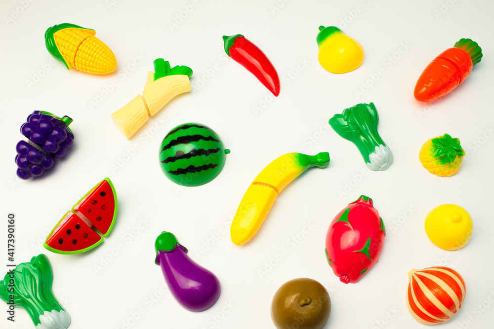 Creative pattern of toy fruits and vegetables on a white background. Minimal food concept.