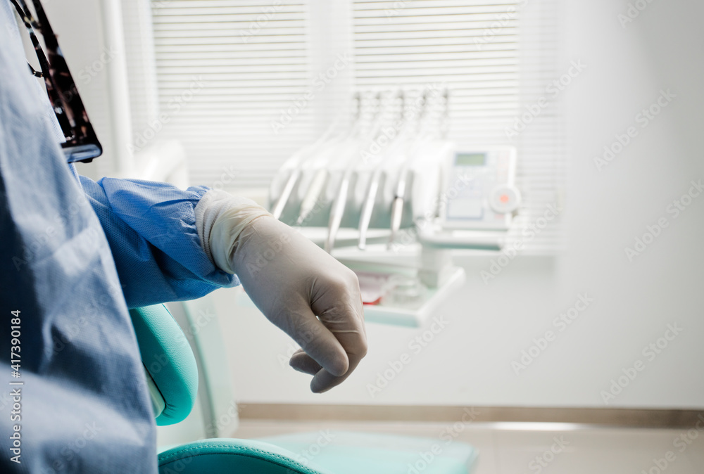 hand of a dentist, with specialized material and equipment in the background. hand of a dentist, with specialized material and equipment in the background.