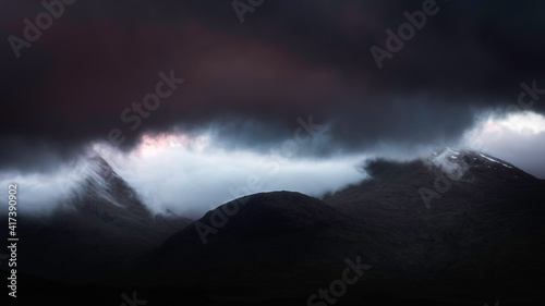 Extreme weather conditions in Scottish Highlands at dawn.Dark clouds over mountain peaks and cloud inversion in the valley.