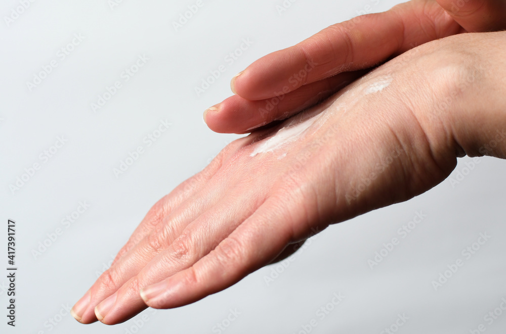 Fototapeta premium Female Hands Natural Manicure White Background Applying Moisturizer Hand