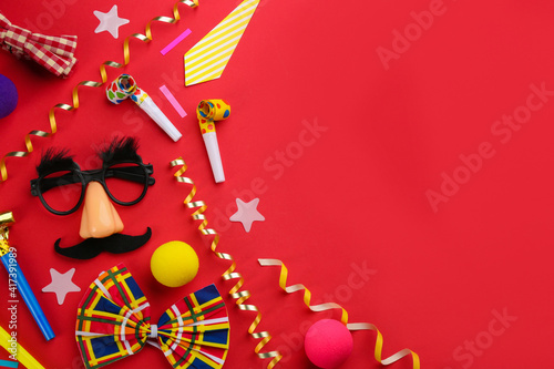 Flat lay composition with clown's accessories on red background. Space for text