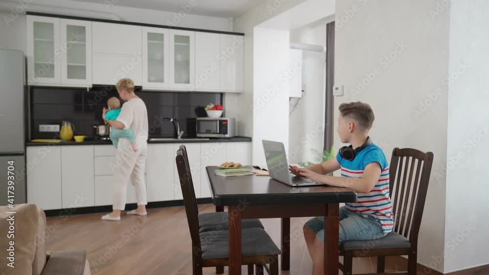 Woman with baby cooking while eldest son studying Woman with baby cooking while eldest son studying