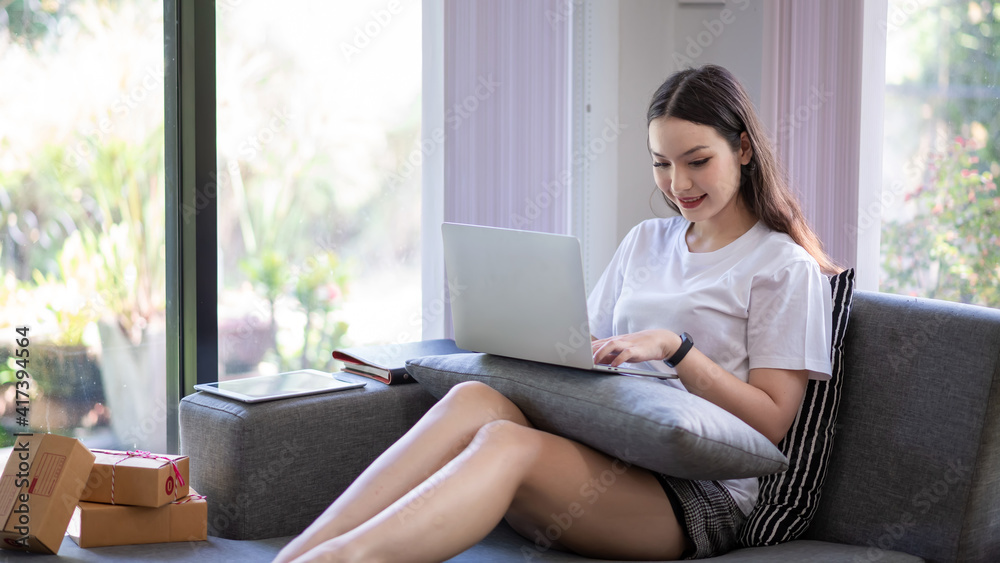 Young Asian woman shopping online at home with parcels to prepare for delivery. Young Asian woman shopping online at home with parcels to prepare for delivery.