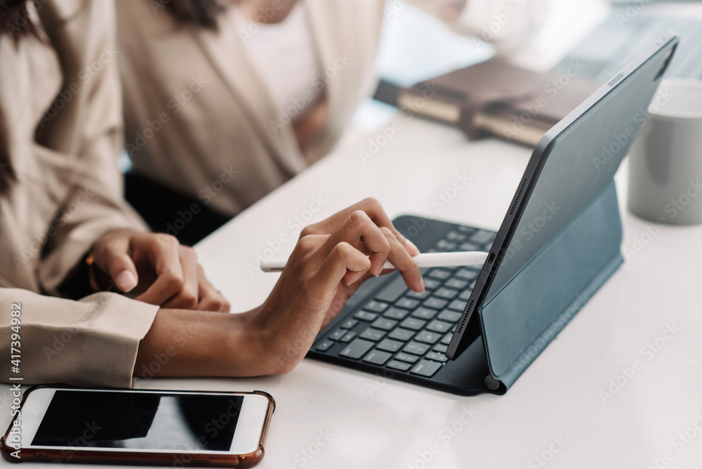 Close-up of woman hand holding a pen working using tablet at office desk. Close-up of woman hand holding a pen working using tablet at office desk.