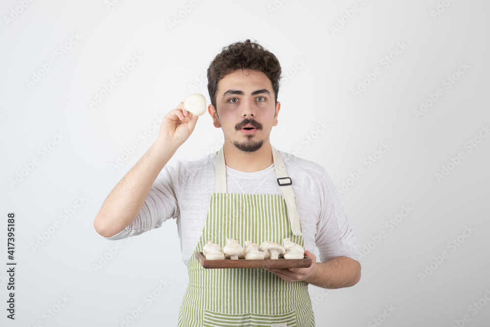 Portrait of male cook showing raw mushrooms on white background Portrait of male cook showing raw mushrooms on white background