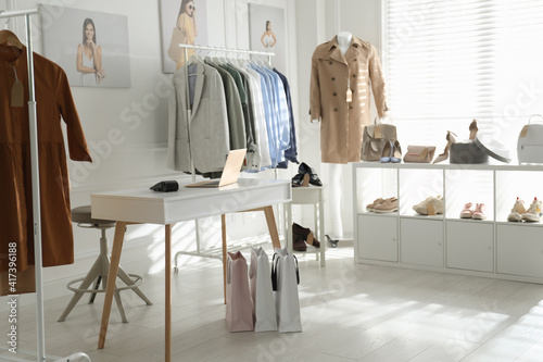 Collection of stylish women's clothes, shoes and accessories in modern boutique photo