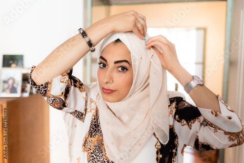 Young muslim woman putting on hijab headscarf photo