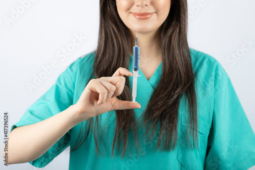 Portrait of female doctor holding a large syringe.