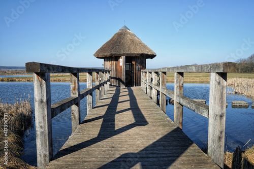 Fototapeta Naklejka Na Ścianę i Meble -  Steg der in einem See mündet mit einer Hütte im Mittelpunkt