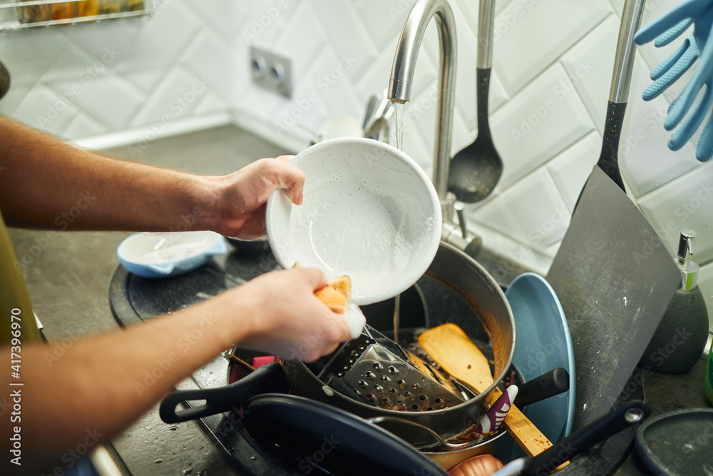 Young man washing dishes in the kitchen.