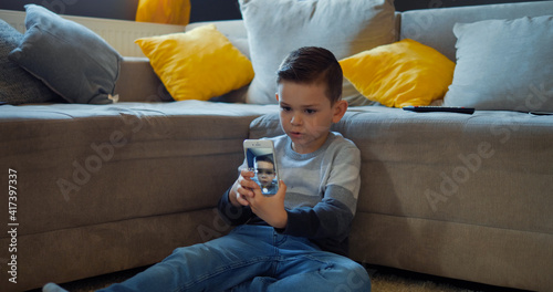 Little boy is taking pictures on the phone, taking selfies at home for social networks